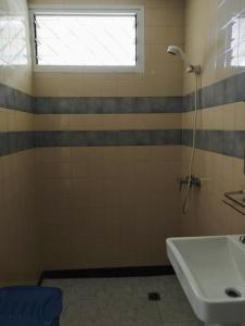 a bathroom with a shower and a sink and a window at Charmante maison Riviera Golf Jardins in Abidjan