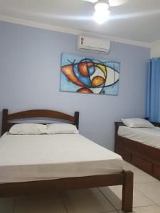a bedroom with two beds and a painting on the wall at Casa de praia na Reserva do Peró em Cabo Frio - familiar com piscina in Cabo Frio