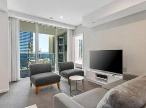 un salon avec un canapé, des chaises et une télévision dans l'établissement Paradise City Lights - Privately Managed Luxury Suite on Hilton Surfers Paradise Free Carpark, à Gold Coast