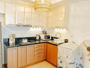 - une cuisine avec des placards en bois et un four micro-ondes blanc dans l'établissement Venice Luxury Residences Studio McKinley Hill, à Manille