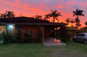 a house with a car parked in front of a sunset at Refúgio do Bosque in Penha