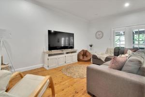 a living room with a couch and a flat screen tv at The Macleay - Poolside Entertainer, Pets Allowed in Wagga Wagga