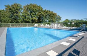 a large blue swimming pool with chairs and trees at Oud Kempen Bungalow 41 in Stavenisse +12 photos
