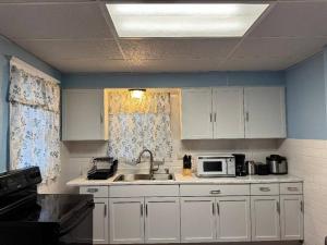 a kitchen with white cabinets and a sink and a microwave at Getaway at Niagara in Niagara Falls