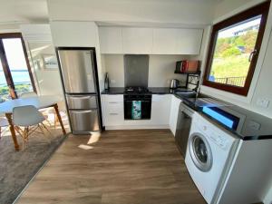 a kitchen with a refrigerator and a washer and a table at Stunning sea, city & mountain views, 2 bedroom home, free parking, in brand new condition in Christchurch