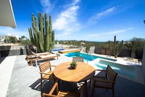 a patio with a wooden table and chairs and a cactus at Baja Winds Sky in La Ventana