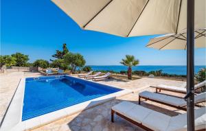 a swimming pool with an umbrella and the ocean at Villa Toma in Škunca