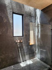 a bathroom with a glass shower with a window at ACOGEDORA CASa EN MALINALCO in Malinalco