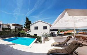 un patio con piscina, ombrellone e sedie di Villa Mondeo a Rogoznica (Rogosnizza)