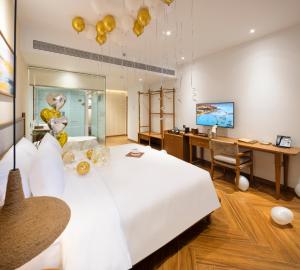 a bedroom with a large white bed and a desk at Iconic Long Hai Hotel in Long Hai