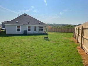 a yard with a white house and a fence at Quite big home near Tesla & COTA in Del Valle