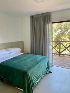 a bedroom with a bed and a large window at Praia do Forte - Casa linda 3 quartos in Mata de Sao Joao