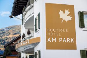 a sign for a hotel on the side of a building at Boutique Hotel Am Park in Valdaora