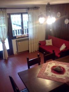 ein Wohnzimmer mit einem roten Sofa und einem Tisch in der Unterkunft Petit Maison - Valtournenche - CIR VDA Valtournenche no 0392 in Valtournenche