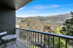 a balcony with a table and chairs and mountains at Byadbo 5 in Thredbo +6 photos