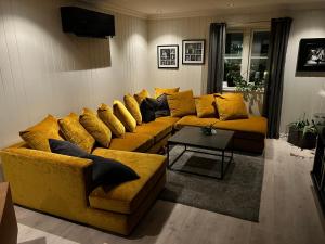 a living room with a yellow couch with yellow pillows at Romslig hus med jacuzzi, spillrom og stor terrasse in Fredrikstad
