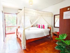 a bedroom with a canopy bed with pink pillows at Aphilapa House in Chiang Mai