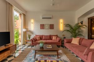 a living room with two red couches and a tv at La Verona by The Blue Kite - 2 & 3 BHK Villas in Assagao with Private Pool, Garden, Caretaker, Kitchen & Security in Assagao