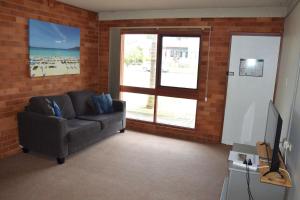 a living room with a couch and a television at Anglers Lodge 4 - bring your own linen in South West Rocks