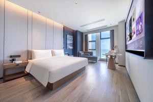 海口市にあるAtour Hotel Haikou Binhai Avenue Xixiu Beachの大きな白いベッドとテレビのある寝室