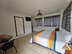 a bedroom with a bed with a rainbow striped blanket at Hotel Colonial Campestre in UniÃ³n JuÃ¡rez +13 photos