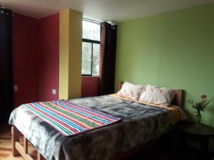 een slaapkamer met een bed met groene muren en een raam bij Hostal El Viajero in Surcubamba