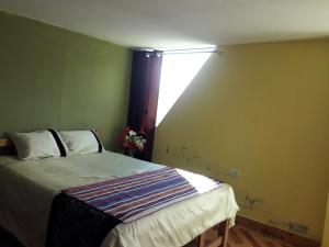 een slaapkamer met een bed en een raam erin bij Hostal El Viajero in Surcubamba