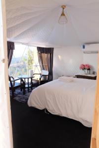 a bedroom with a white bed and a table at Viman keeree doichang วิมานคีรี ดอยช้าง in Ban Huai Khai