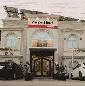 a smart hotel with cars parked in front of it at Swarg Hotel in Sāhīwāl