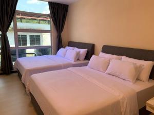 two beds sitting in a room with a window at T Lodge, Kapit in Kapit