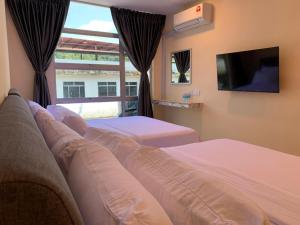 a bedroom with two beds and a tv and a window at T Lodge, Kapit in Kapit