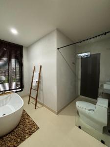 a bathroom with a tub and a toilet and a sink at The Episode Boutique Hotel in Suratthani