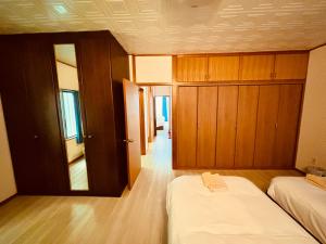 1 dormitorio con 2 camas y armarios de madera en Umikaji Base WAKASA, en Naha