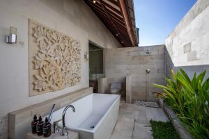 a bathroom with a bath tub and a toilet at Enchanting Canggu Villa in Tumbak Bayuh