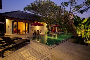 a house with a swimming pool and a wooden deck at Enchanting Canggu Villa in Tumbak Bayuh