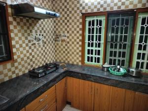 a kitchen with a counter top with a stove at Honeycomb Homestay Ground Floor in Palni