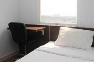 a bedroom with a desk and a bed and a chair at Homey and Minimalist 2BR at Patraland Urbano Apartment By Travelio in Bekasi +18 photos