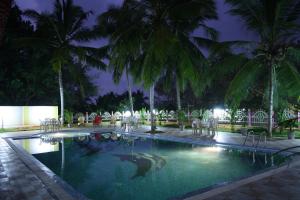 - une piscine avec des chaises et des palmiers la nuit dans l'établissement The Travancore Palace Beach Resort, à Kovalam 43 autres photos