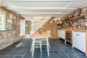 Una cocina con una mesa y sillas en una habitación. en Castaways, Cottage With Sea Views, Lush Gardens & Patio By the Beach, en Sennen