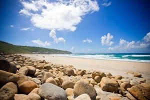 a beach with a bunch of rocks and the ocean at Little Petra, Cottage With Garden, Superb SeaViews in Amazing Location in Sennen +22 photos