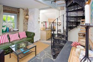 a living room with a green couch and a staircase at Little Petra, Cottage With Garden, Superb SeaViews in Amazing Location in Sennen