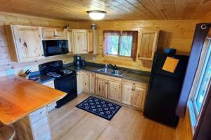 a kitchen with wooden cabinets and a black refrigerator at Lakeside 2 Bedroom Wolfs Den Cabin On Kab in Kabetogama
