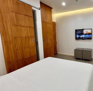 a bedroom with a bed and wooden cabinets and a tv at Cozy Cottage in Kabankalan +3 photos