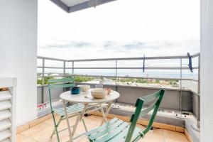 a table and chairs on a balcony with a view of the ocean at Appartement T2 Tampon centre in Le Tampon