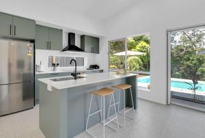 a kitchen with a sink and a counter with stools at Belle Escapes Mer-Sea in Trinity Beach