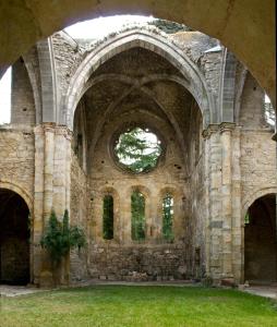 an old stone building with an archway in the grass at Abbaye De Villelongue in Saint-Martin-le-Vieil