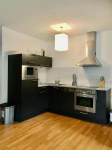 kuchnia z czarno-białymi urządzeniami i drewnianą podłogą w obiekcie Anna 3 by SMR Rauris Apartments - inc Spa and near Gondola w mieście Rauris