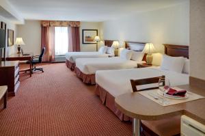 Pomeroy Inn and Suites Dawson Creek في داوسون كريك: غرفة في الفندق بسريرين وطاولة مع كؤوس للنبيذ