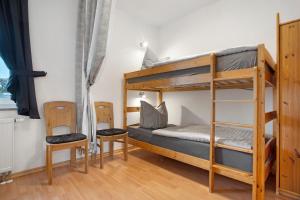 a bedroom with bunk beds and two chairs at Haus A Cappella B6 in Binz +21 photos