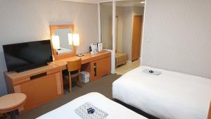 a hotel room with a desk with a television and a bed at West Inn Fuji-Yoshida in Fujiyoshida